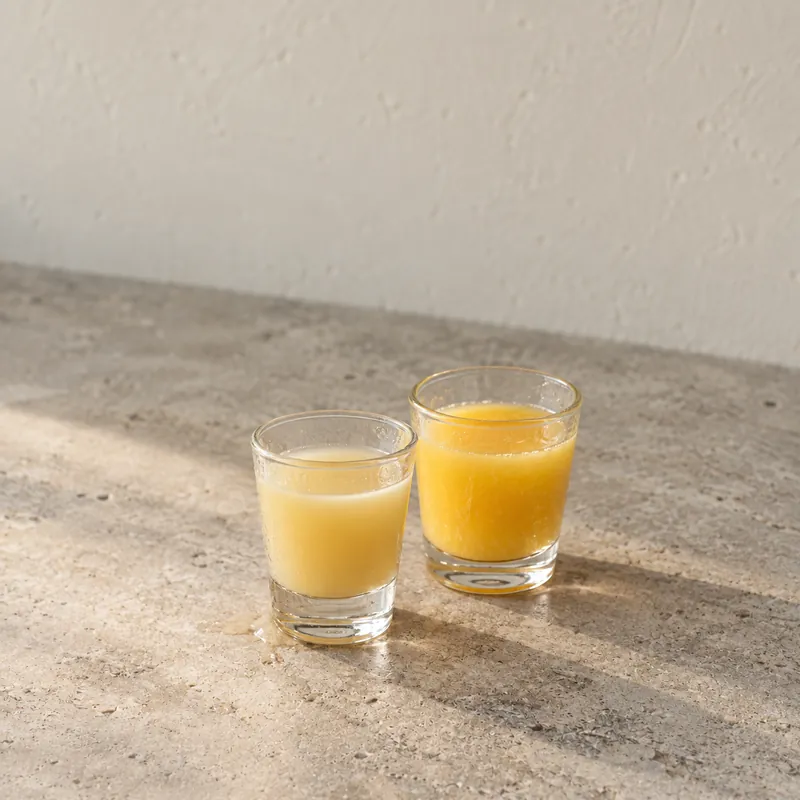 A shot of Kava Moon Signature with a small glass of orange juice